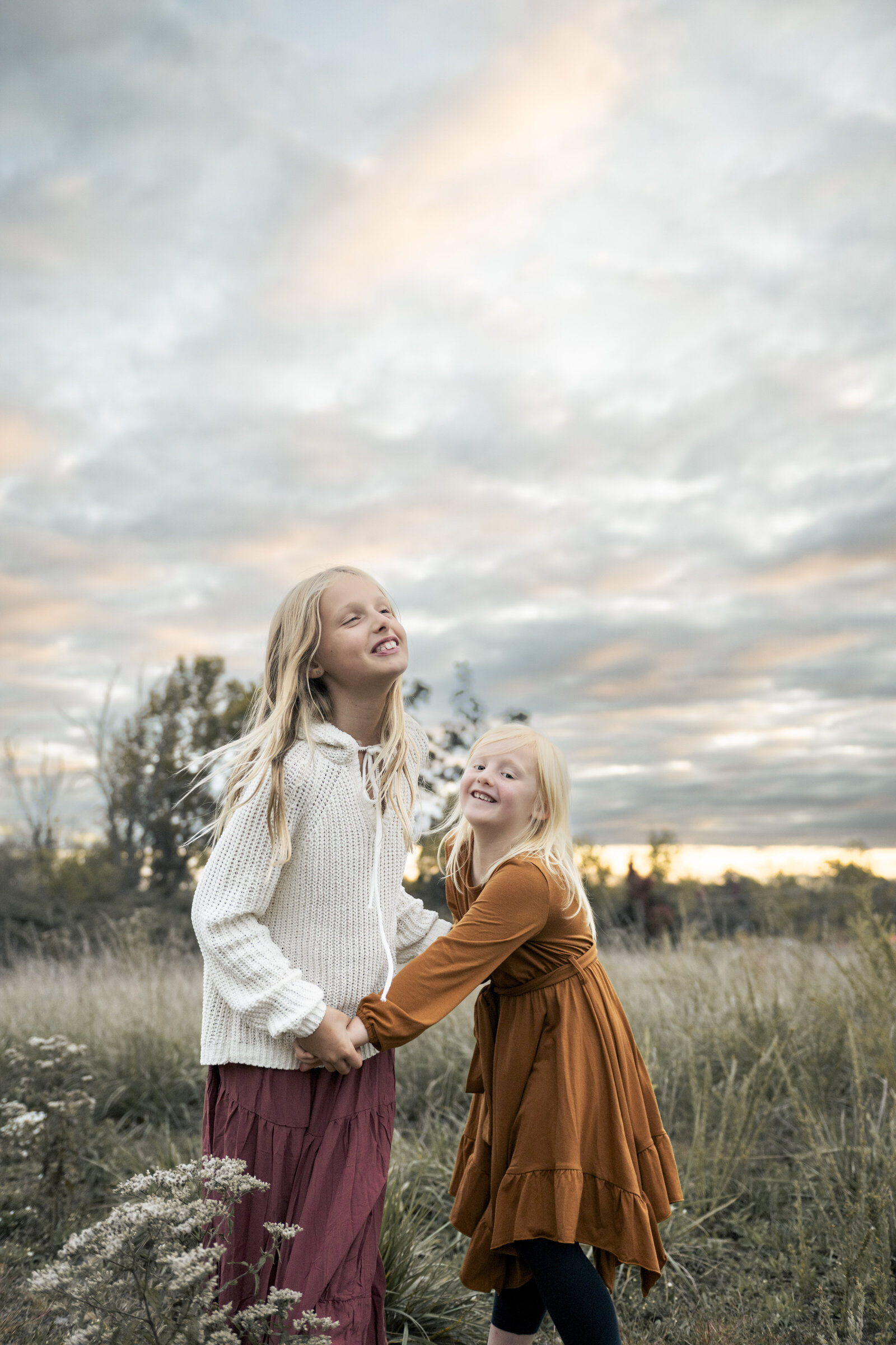 two sisters holding hands dancing in field at Ashburn family session