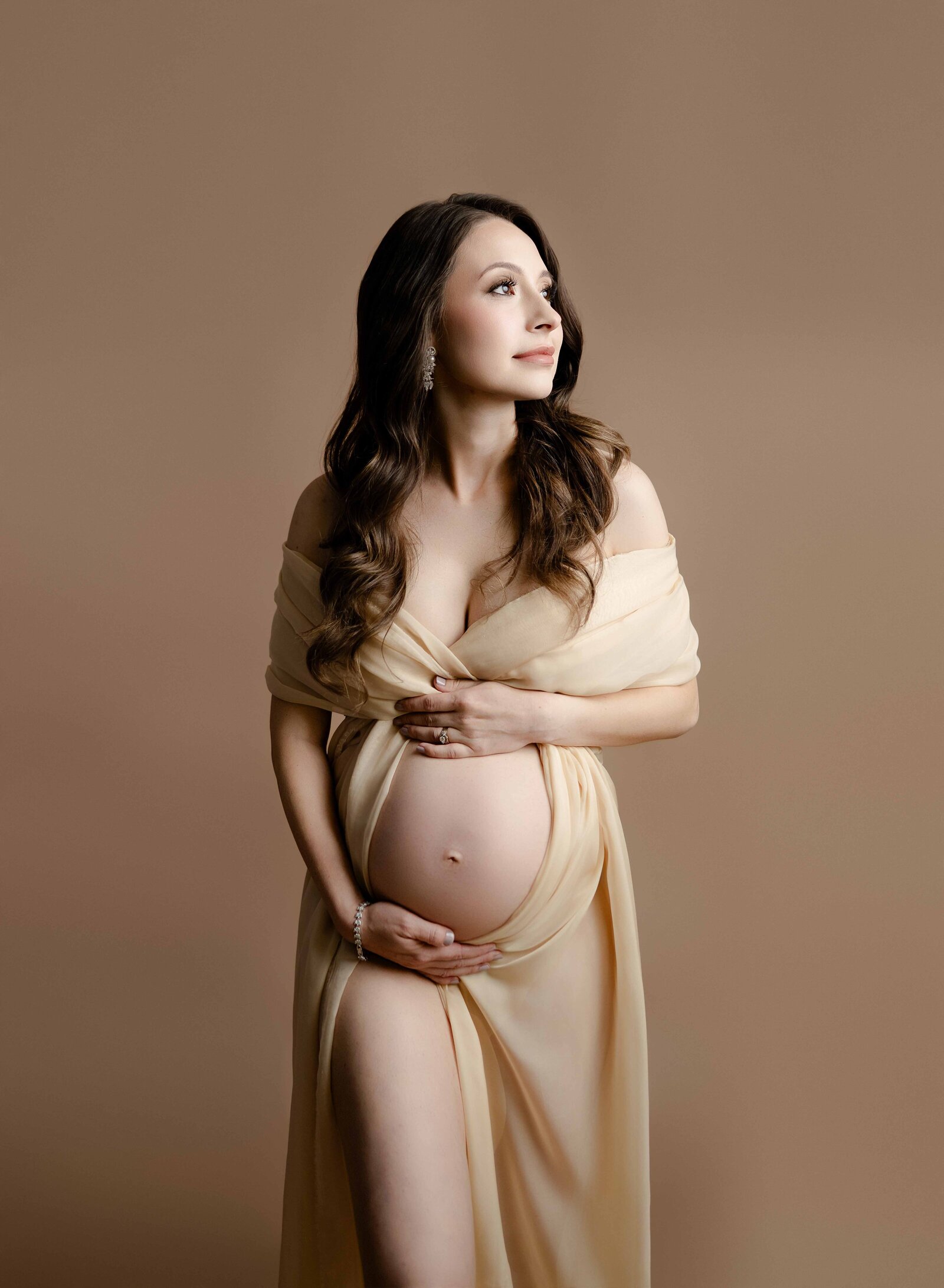 Mom wrapped in cream drape holding baby bump. Maternity Portrait by Jenni Nikki Photography at Atlanta maternity photo studio.