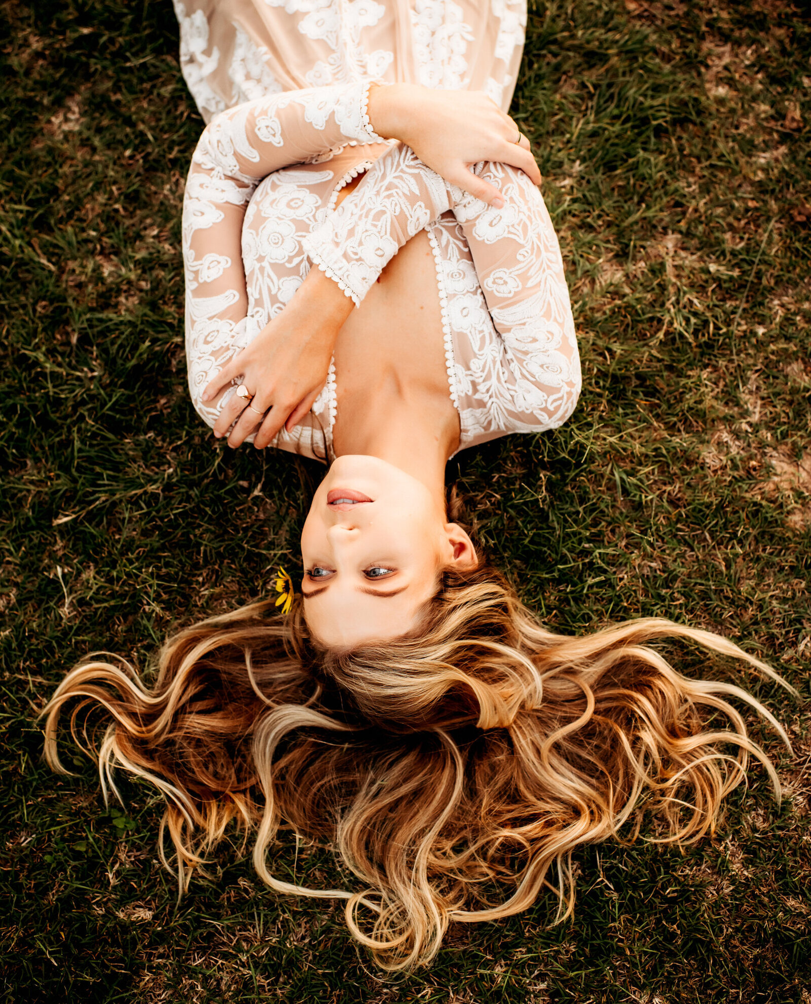 Branding Photographer, a woman lays in the grass, her blonde hair all laid out, she is in a dress