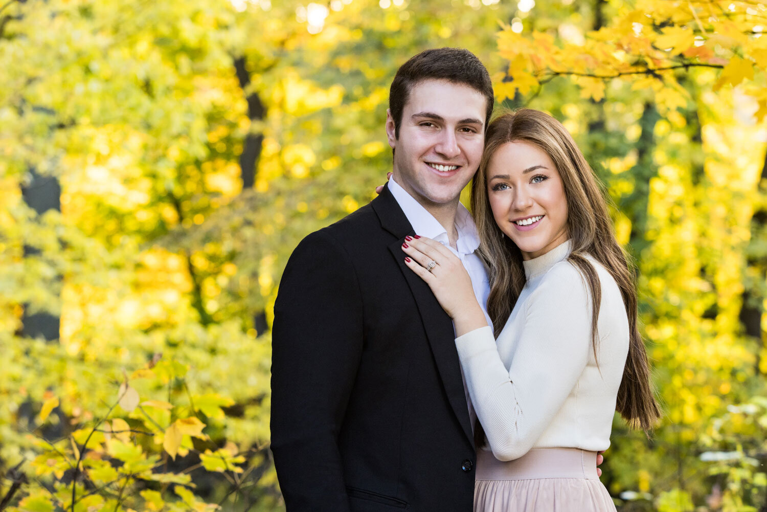 A man in a suit and a woman in a white sweater are posing for a picture.