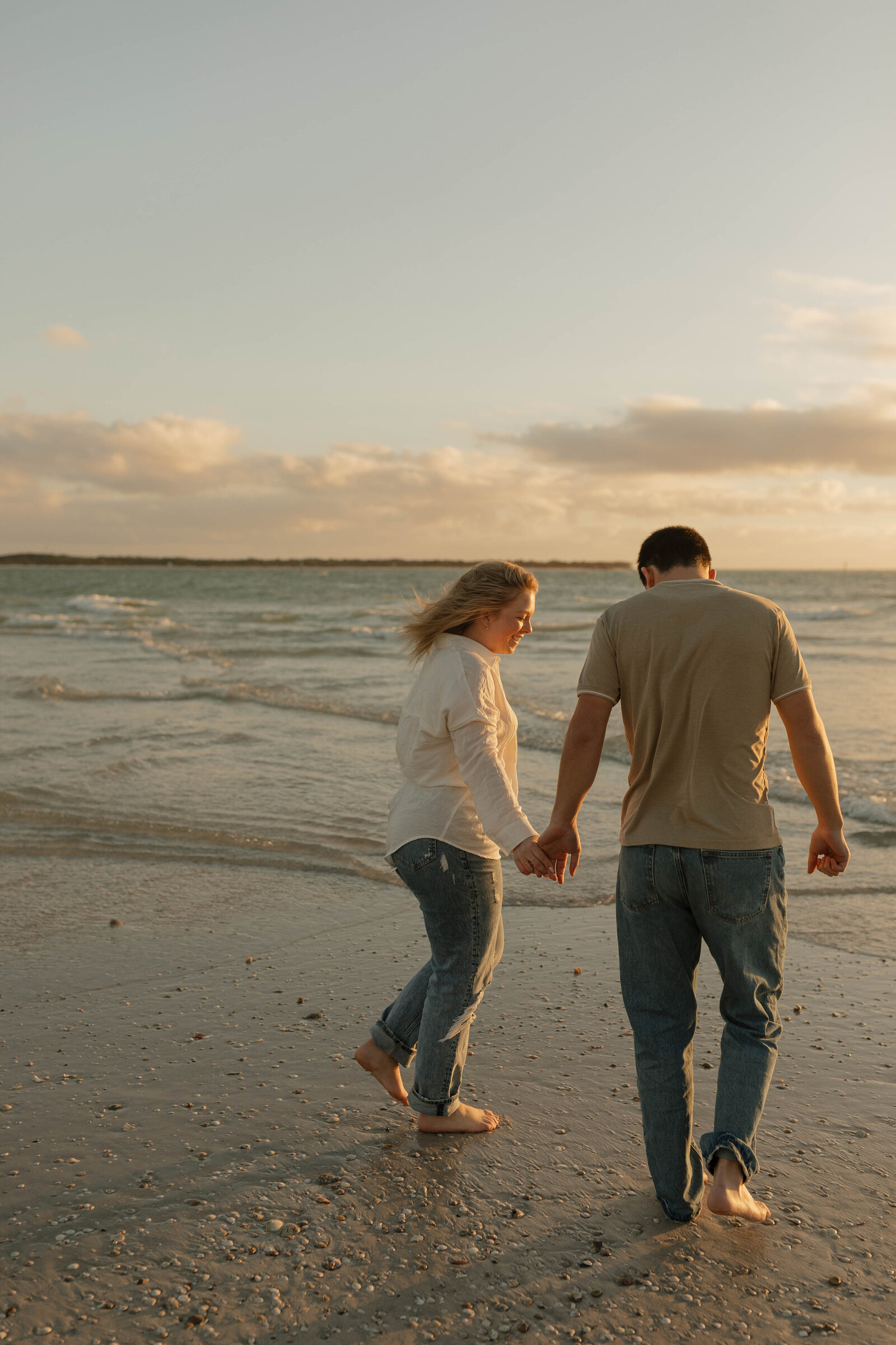 Two people holding hands on the beach during a couples photography shoot.