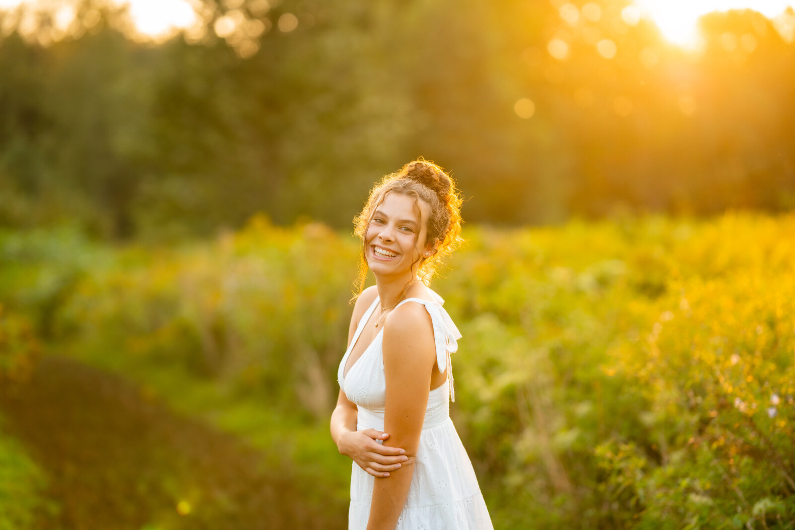 Vermont Senior Photographer with Senior and Green field at golden hour.