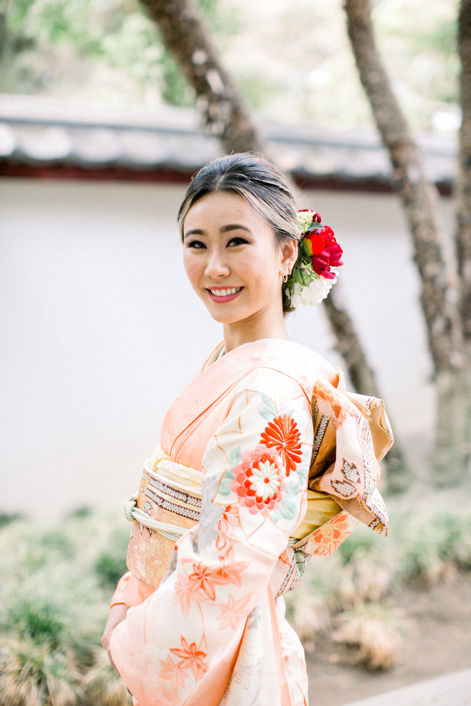 Seijinshiki coming-of-age portrait of a young woman in a soft peach furisode at Brand Park tea house Glendale. Available for kimono rental in Los Angeles | ロサンゼルスで着物レンタル。ブランドパーク日本庭園での成人式、淡い桃色の振袖を着た女性のソロポートレート