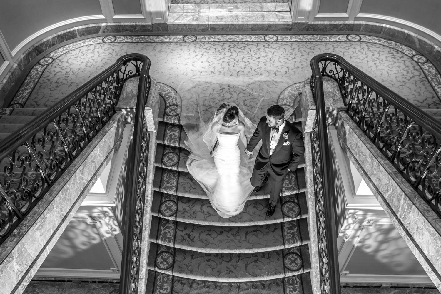 A bride and groom are walking down a set of stairs