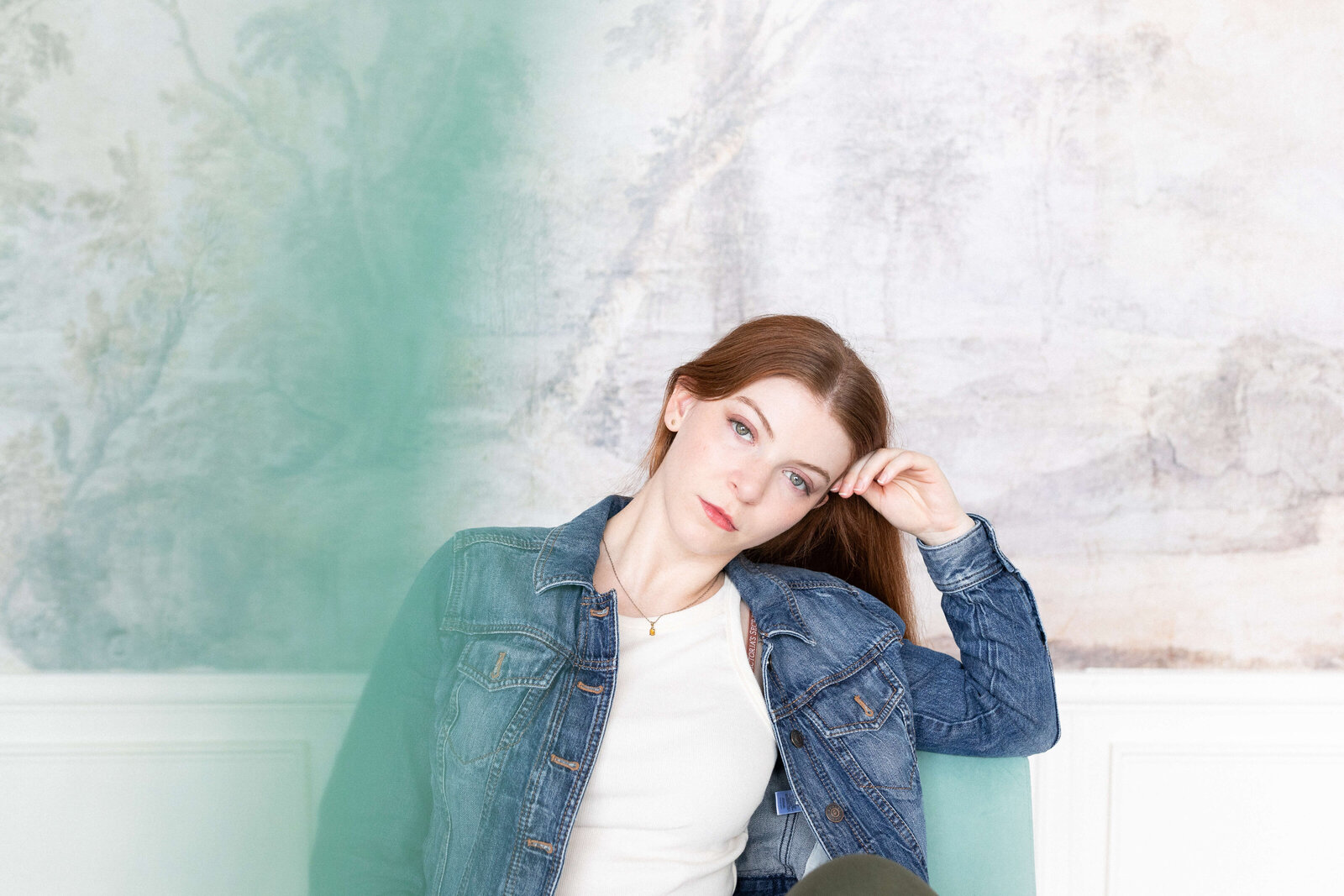 brunette woman with hand on her head posing for camera wearing jean jacket