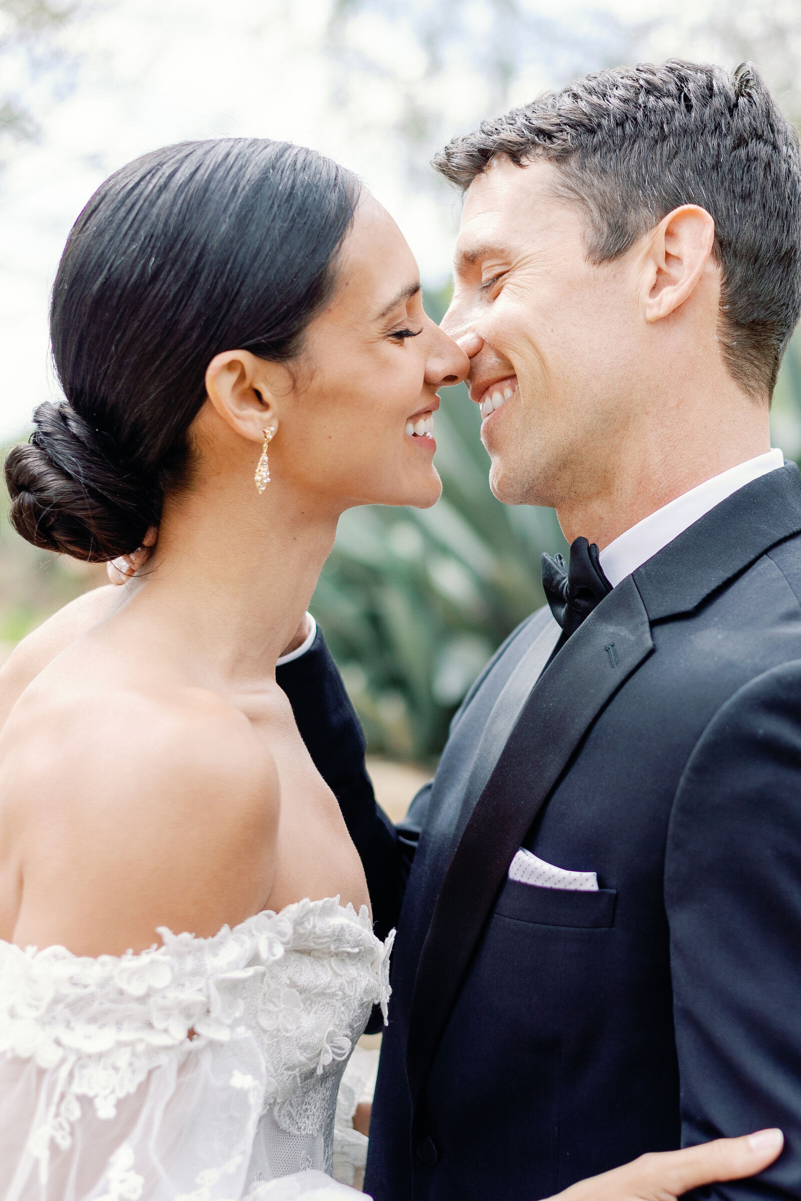 outdoor wedding pictures with bride adn groom laughing together as they lean into one another and begin to embrace before a kiss photographed by wedding photographer bay area