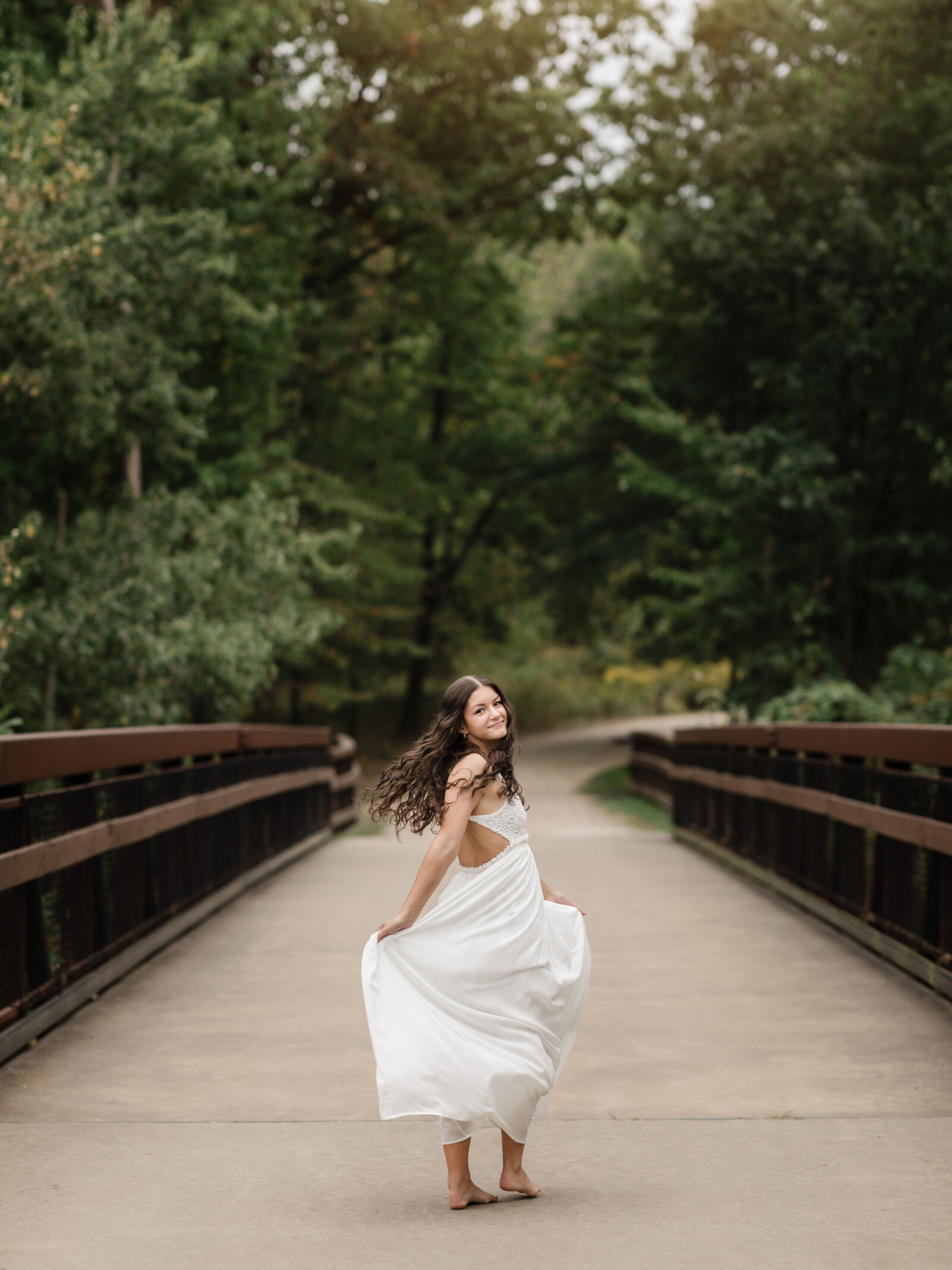high school senior girl in white dress walking on bridge for senior portraits cleveland senior photographer
