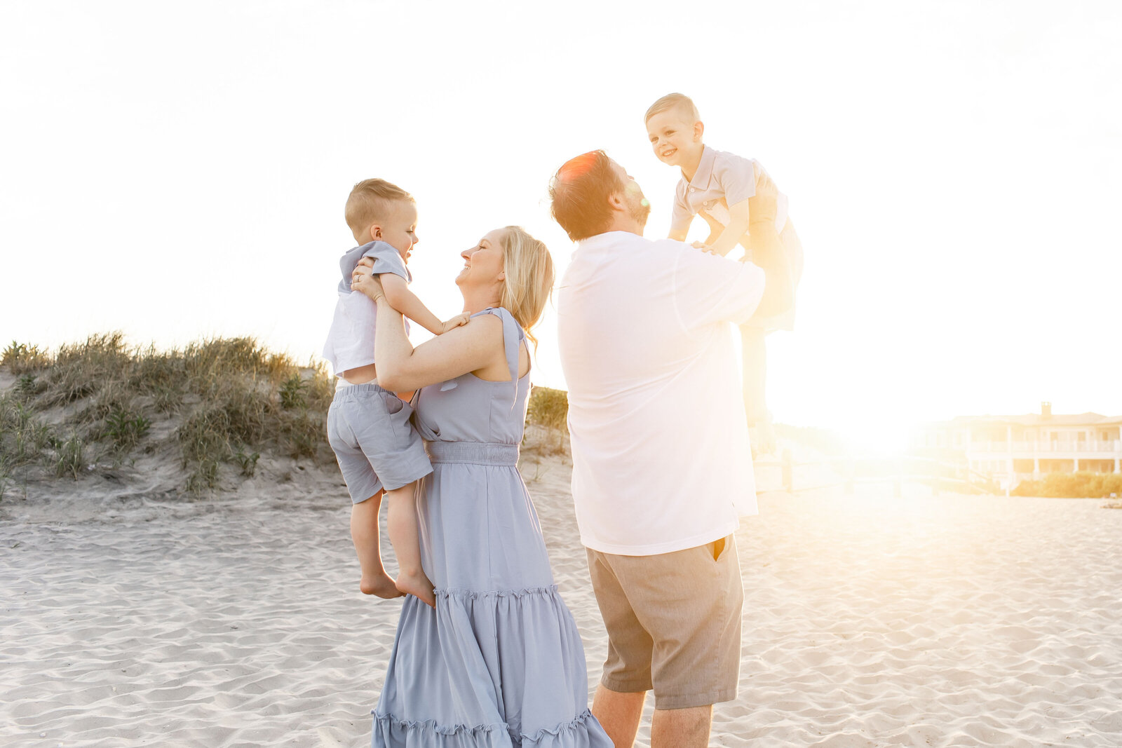 family of four embracing in front of the sunset on ocean city new jersey beach 