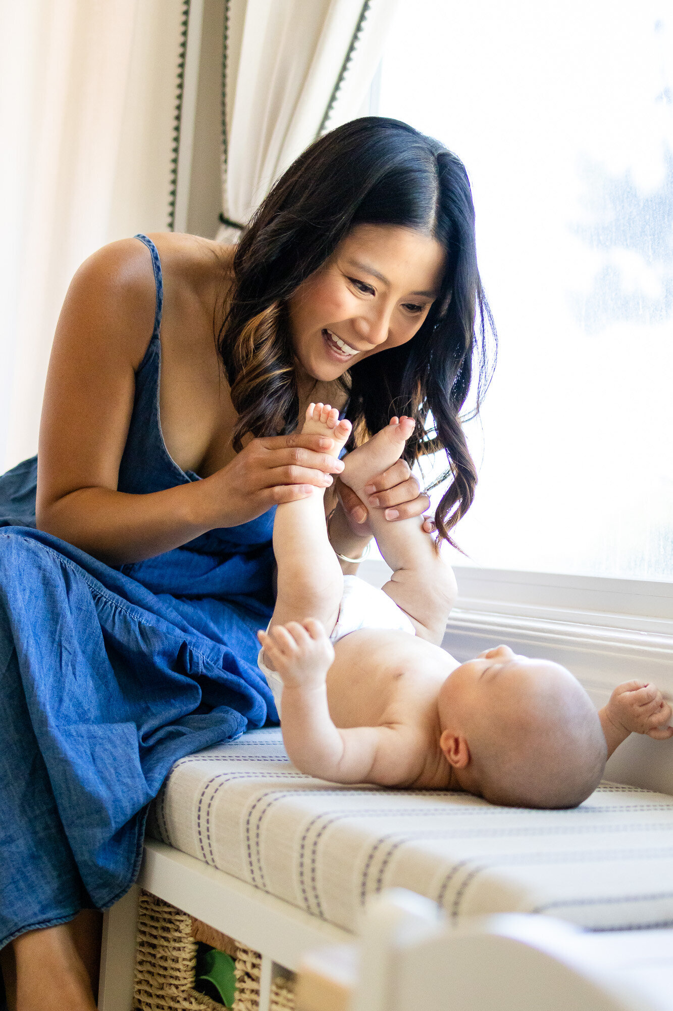 Joyful in-home moment of mom playing with baby’s toes by the window – Book Bay Area Family Photographer - Ellobelle Photography