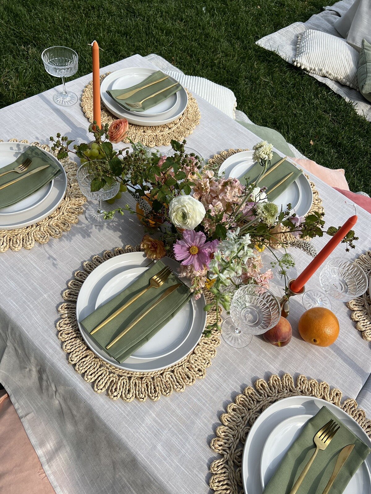 Elegant outdoor table setting with textured placemats, green napkins, fresh florals, and citrus accents, styled by Yours Truly, a wedding planner and designer in New Jersey.