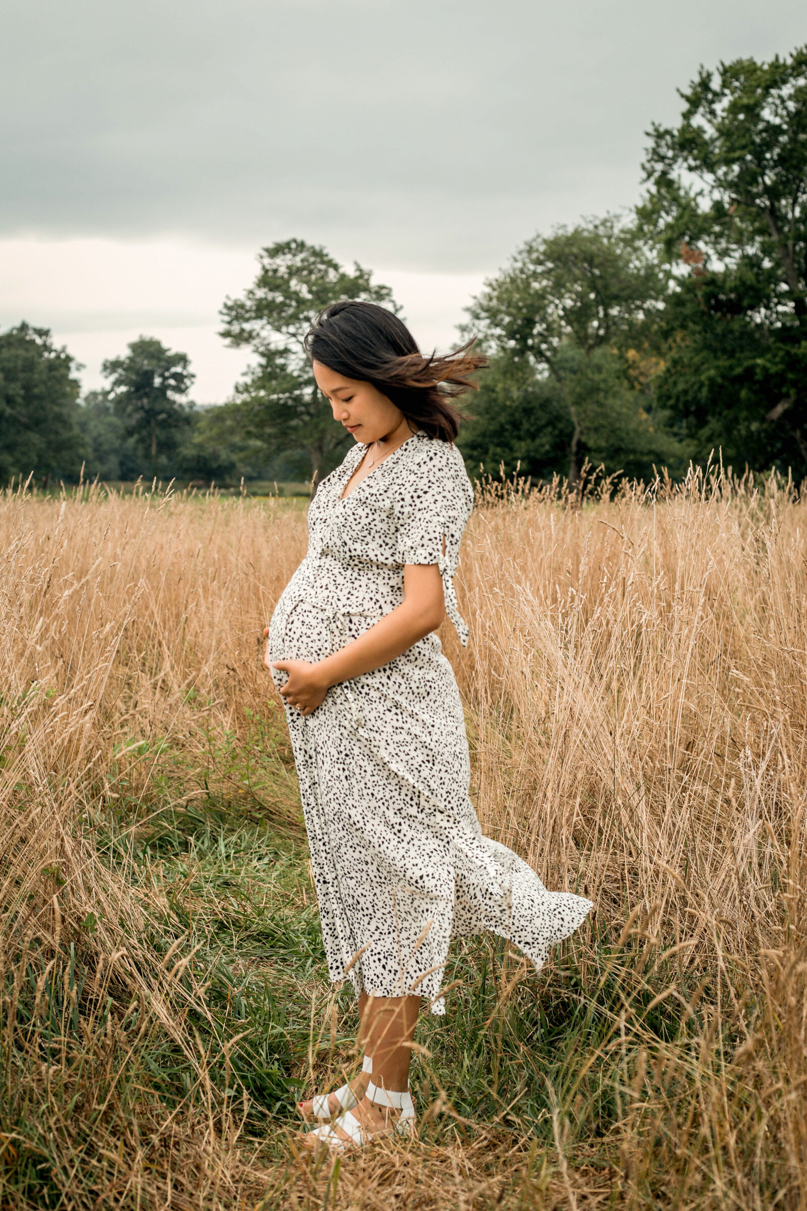 mom to be looking at her belly on a field
