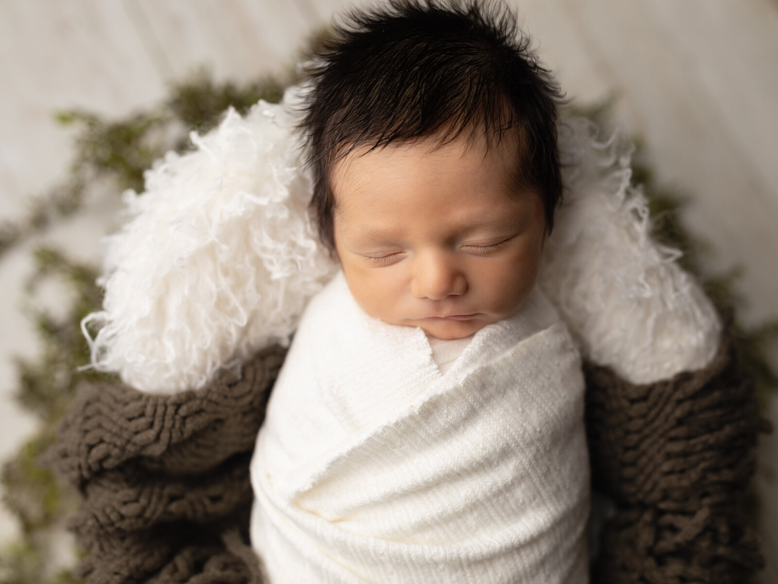 newborn baby boy wrapped in white for studio portrait