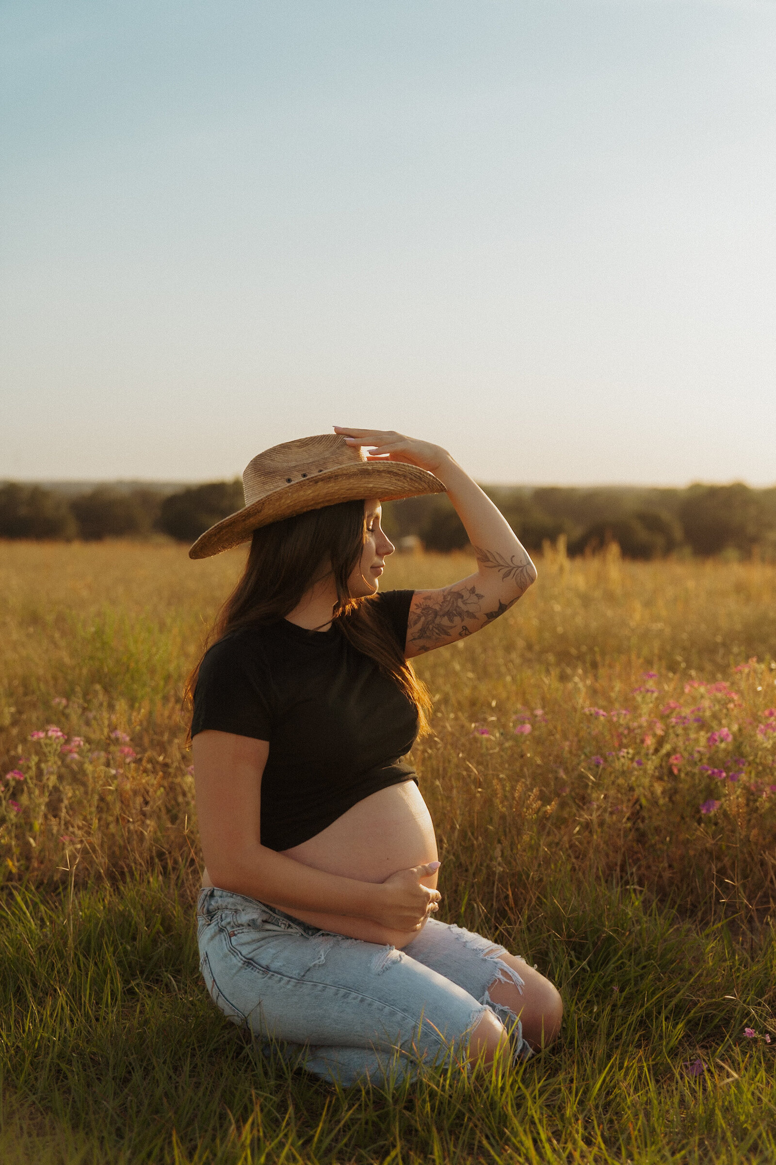 Outdoor maternity session with boho cowgirl vibes, featuring a glowing mama-to-be in a flower-filled Florida field.