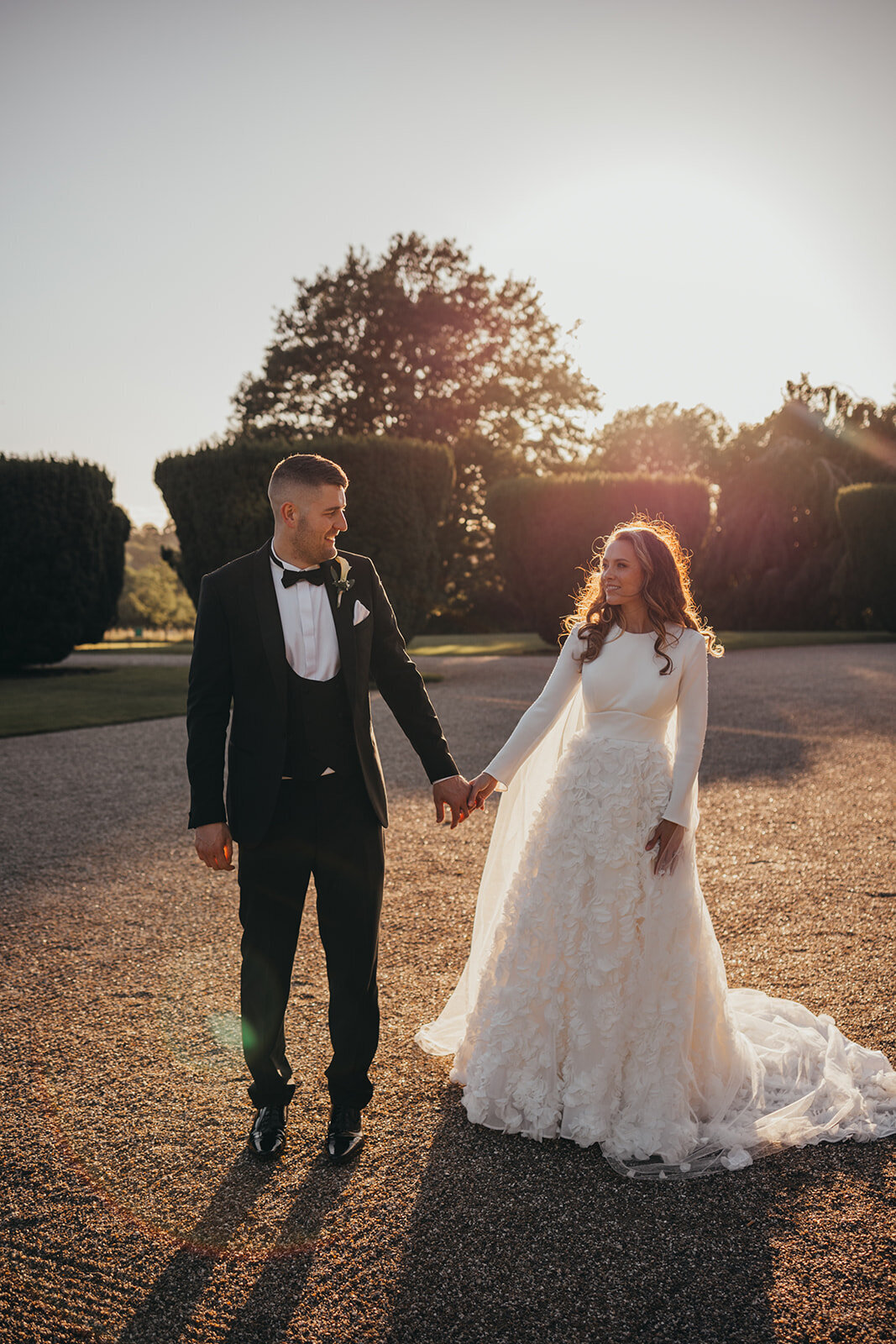 newlywed couple hold hands outside wedding venue
