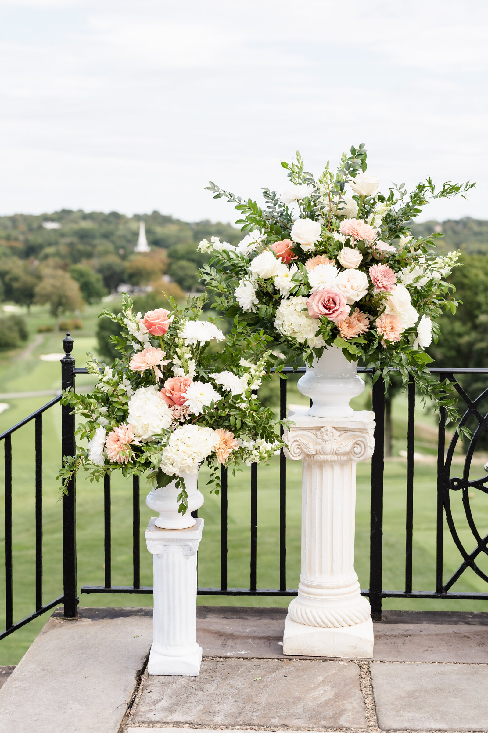 Large floral arrangements stand at the front of the ceremony space overlooking a golf course