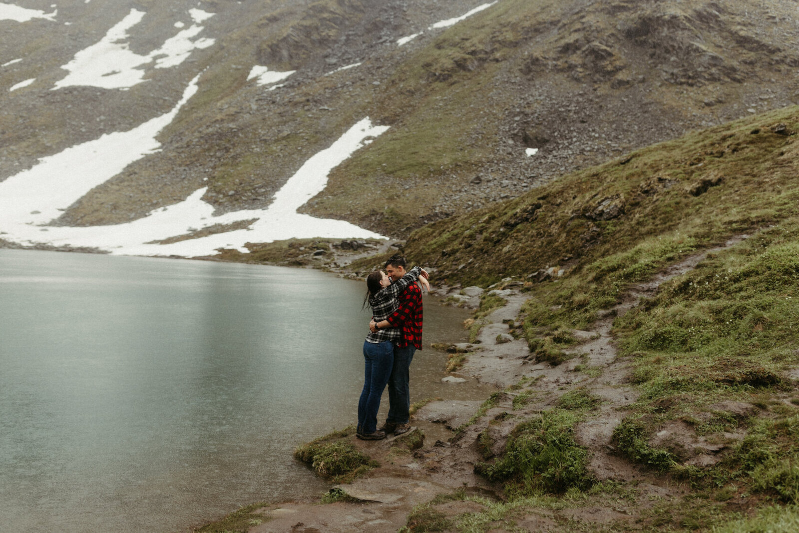 couple standing next to a blue lake