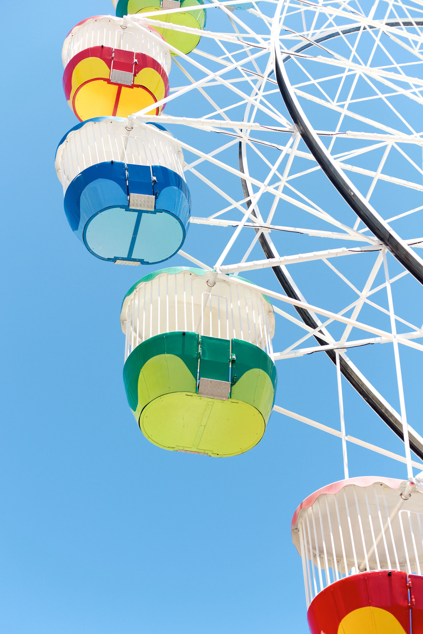 Chelsea Loren branding travel tourism photographer capturing Luna Park ferris wheel colorful baskets in the sky on a blue backdrop in Sydney, Australia