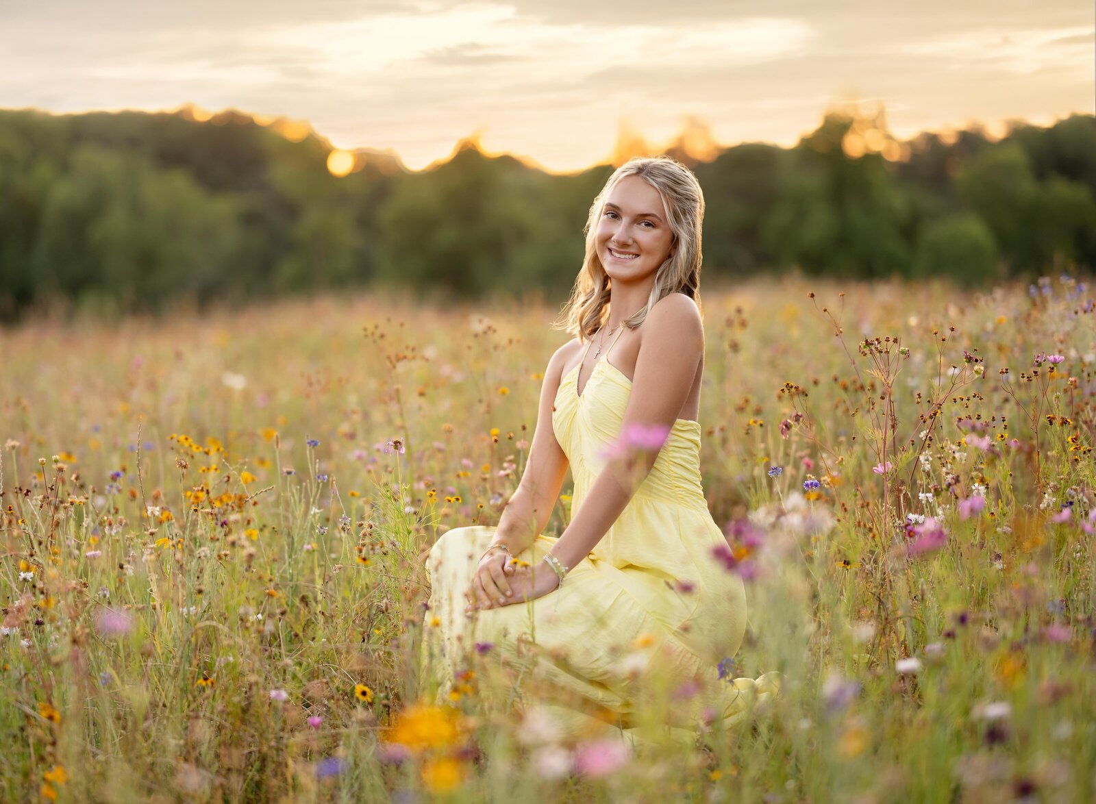 Senior photo of girl kneeling down  in a wildflower field in Atlanta, GA. Graduation photos taken by Jenni Nikki Photography in Atlanta, GA