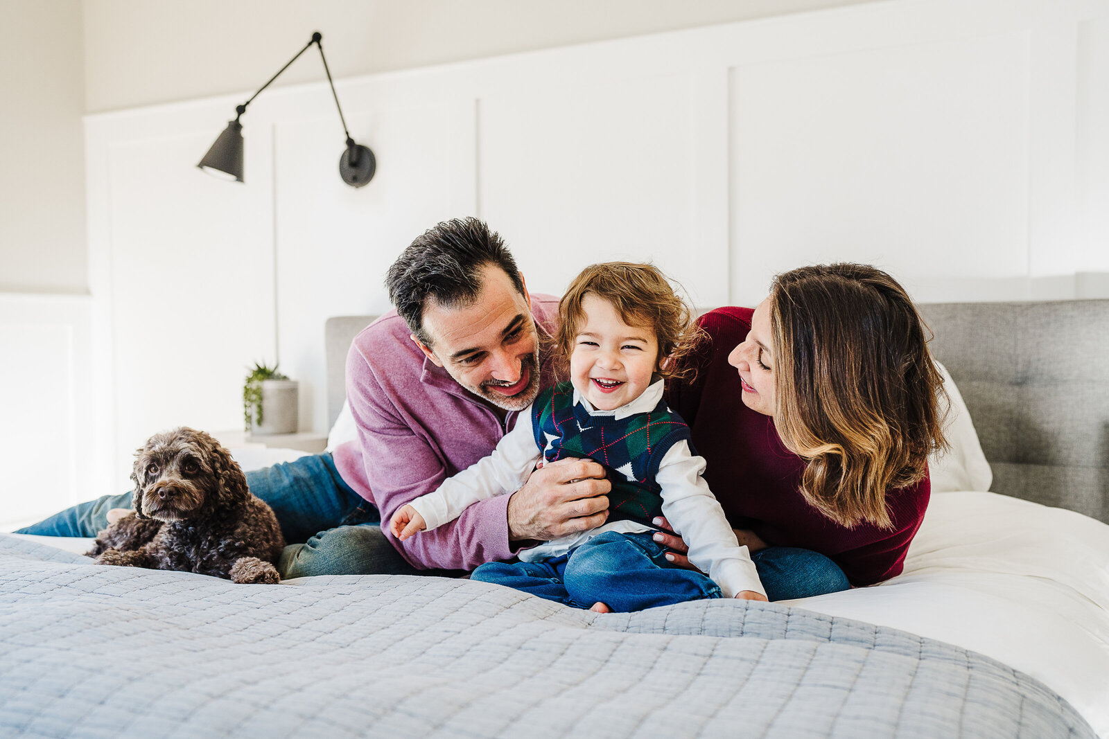 family of three snuggles on bed