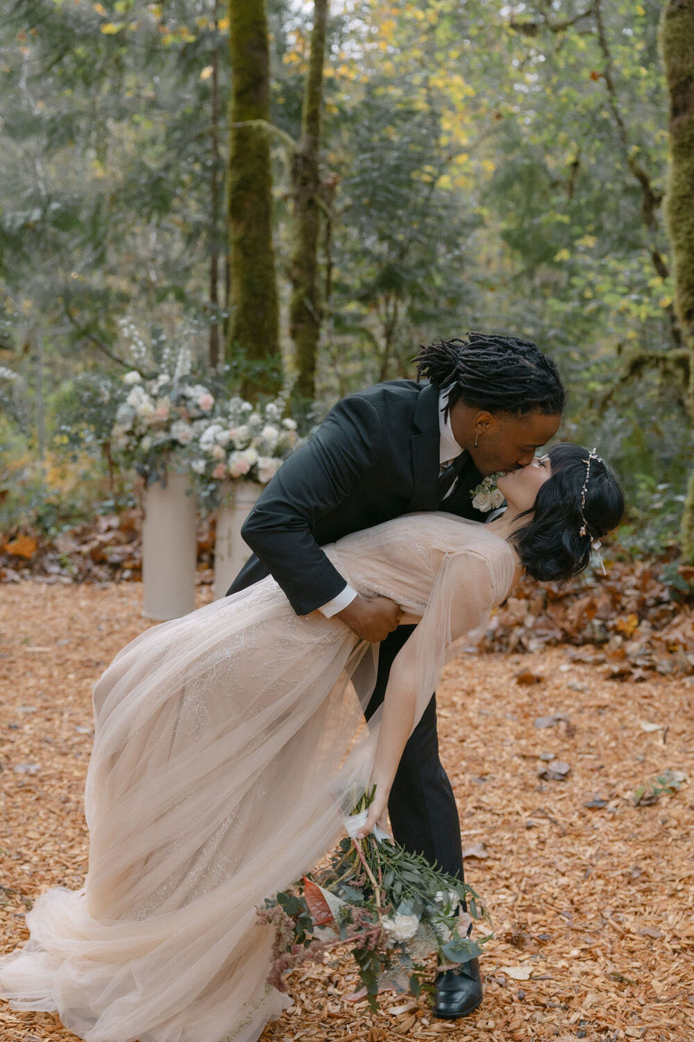 Couple sharing a romantic dip surrounded by lush forest florals