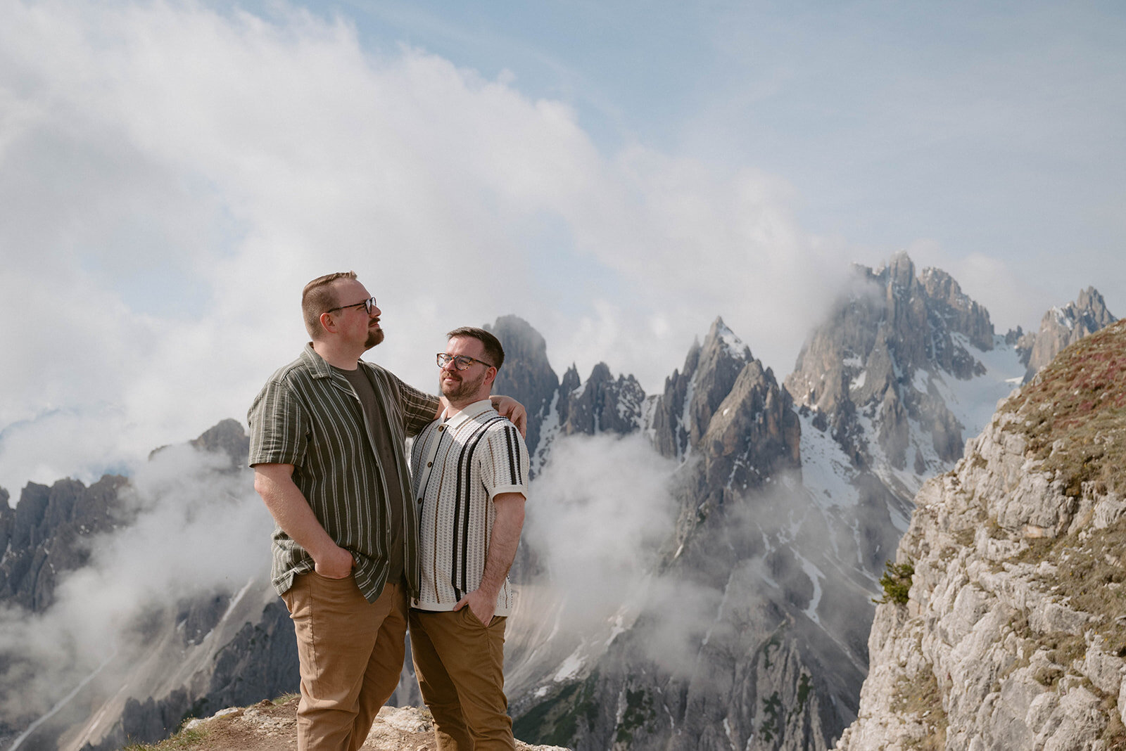queer couple stand front of Dolomites mountains in Italy