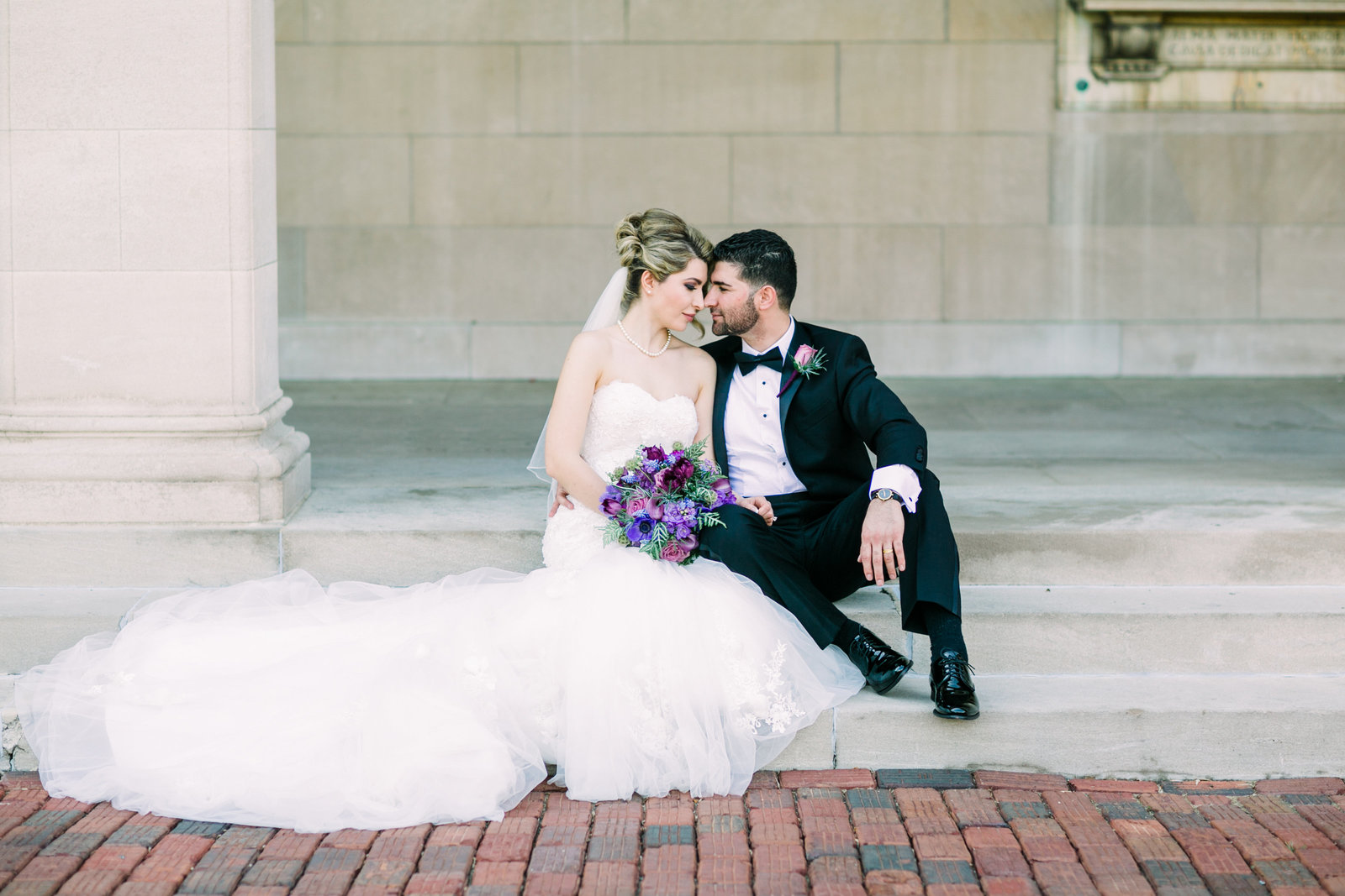 Bride and Groom, Zohra and Fahim, sit side by side on the steps of Washington University.