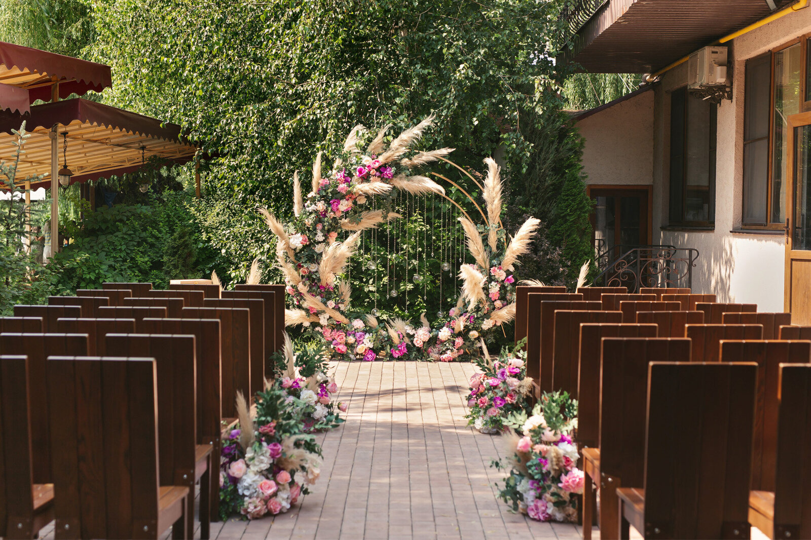 Outdoor wedding ceremony site with pink florals and guests chairs