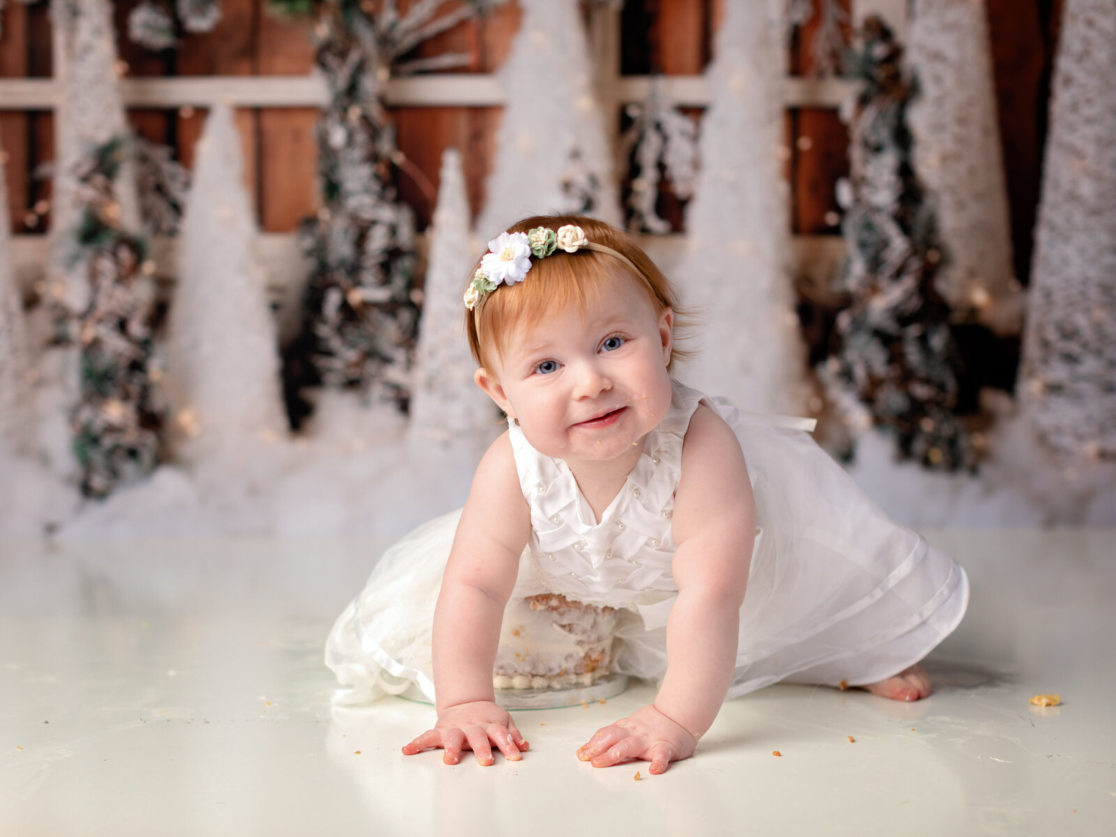 one year old girl in white dress for cake smash photoshoot