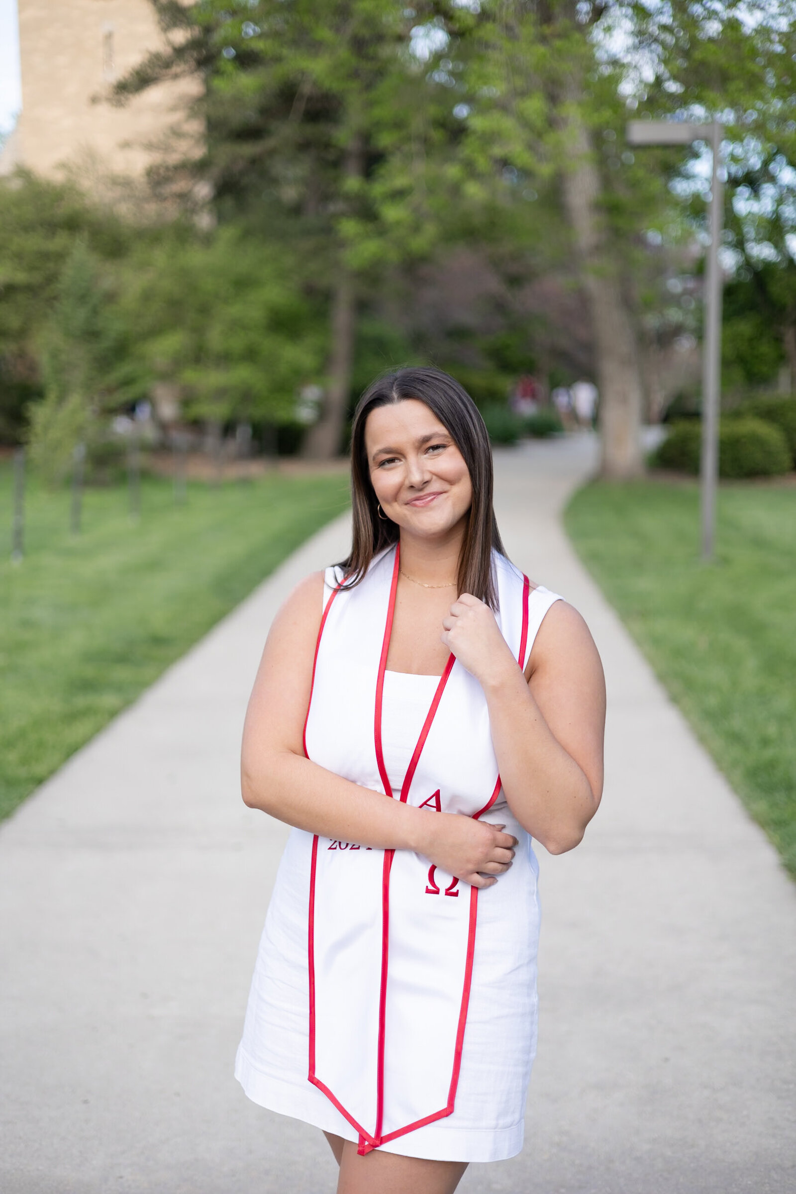 young woman poses on Iowa State's central campus for cap and gown session