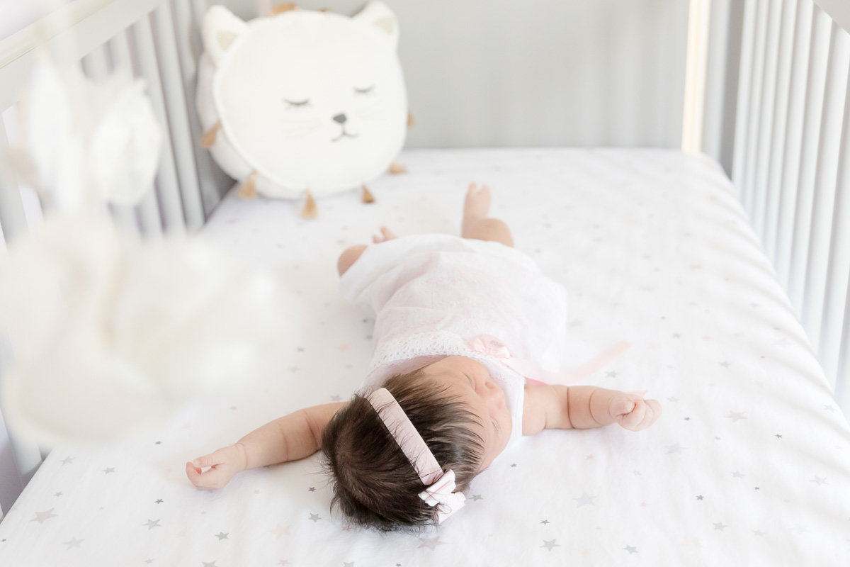 tiny newborn girl sleeps peacefully in white crib