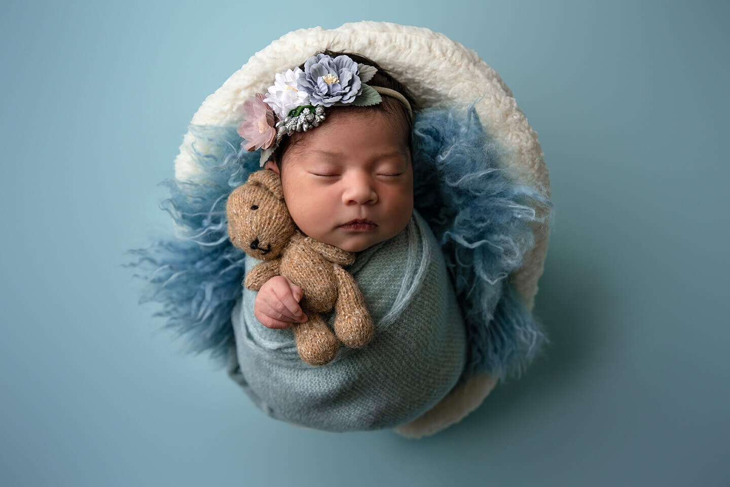 Newborn holding teddy bear