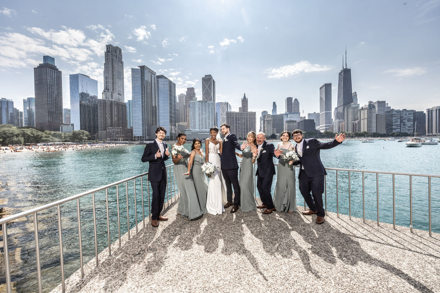 Wedding entourage with the bride and groom standing by the railings with tall buildings view behind