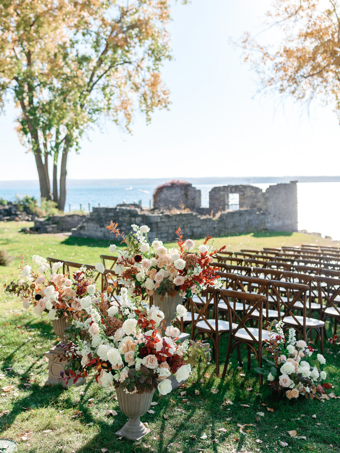 Elegant fall florals and wedding aisle of Inns of Aurora in update New York. Stone ruins and finger lakes in the background.