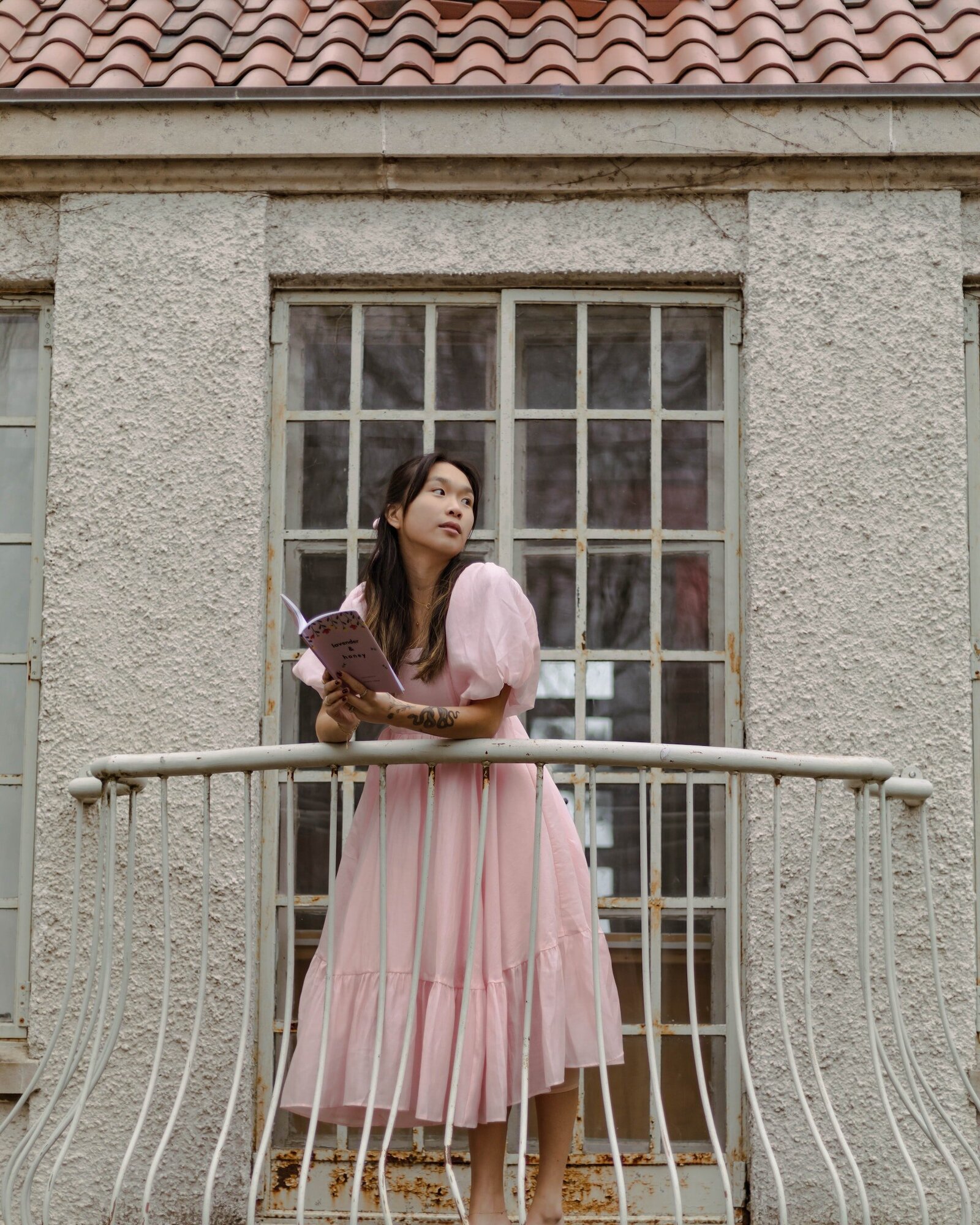 woman-in-long-pink-dress-with-puffy-sleeves-reading-on-balcony