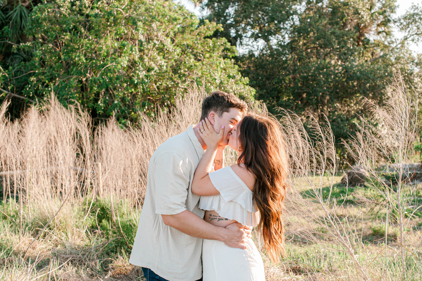 Couple embracing with a kiss during their couples session in a tall grass field in Orlando