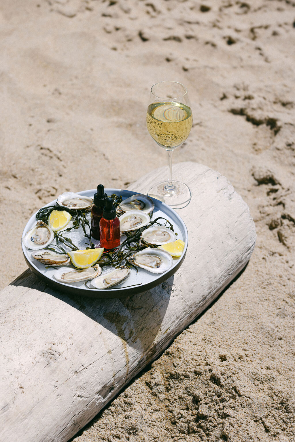 Luxurious beach hotel in Monterey. Boutique hotel photographer showcasing lifestyle experiences. Oysters on the beach with glass of wine.