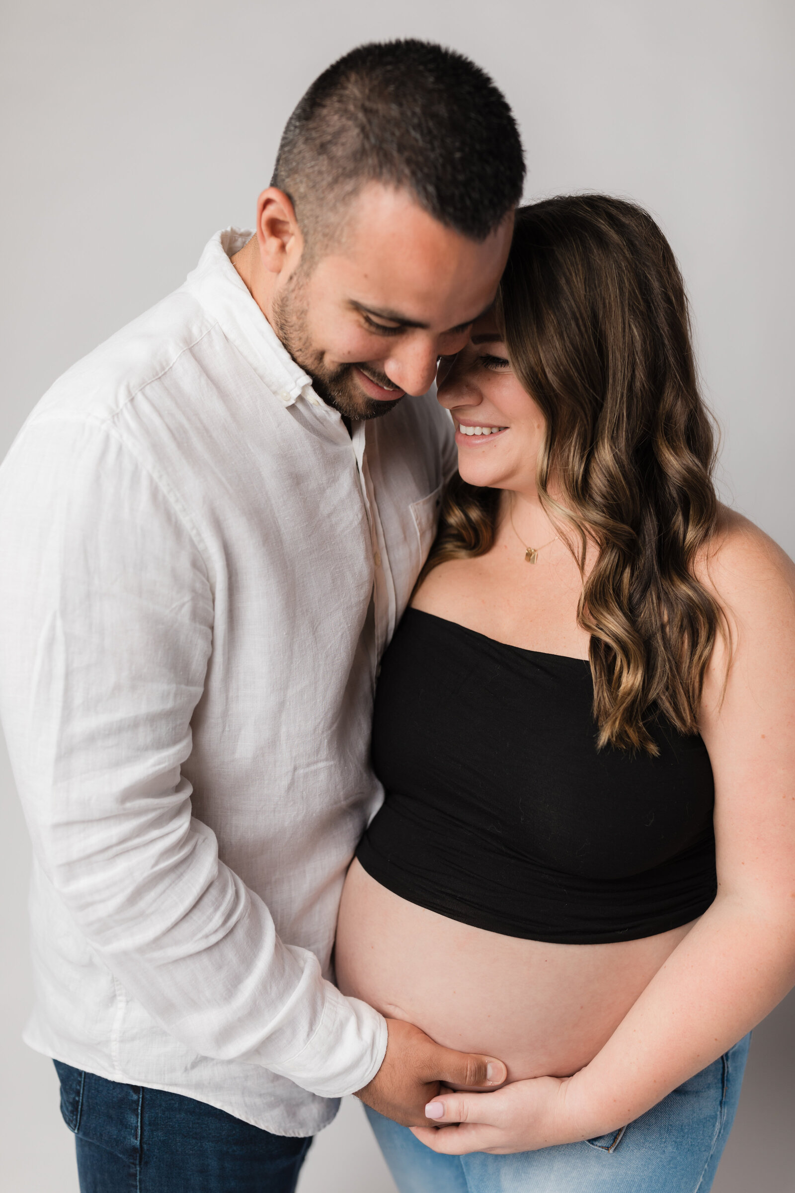 husband and wife holding pregnant belly for studio maternity photoshoot