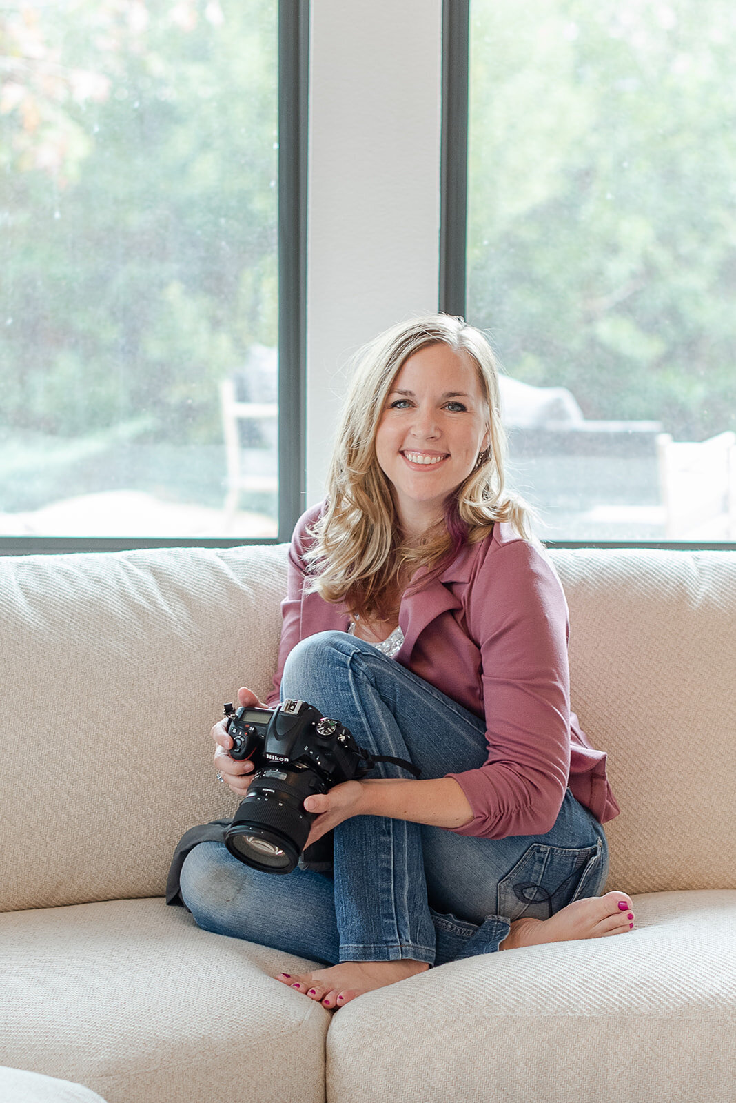 photographer posing with her camera on a white sofa