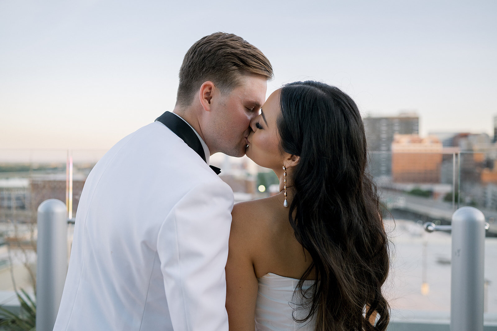 Elegant bride and groom share a romantic moment on the rooftop of the Four Seasons St. Louis — bride in classic off-the-shoulder gown, groom in white tuxedo jacket. Captured by Jordan Grover Photo, a Missouri-based traveling wedding photographer known for refined, documentary-style wedding photography.