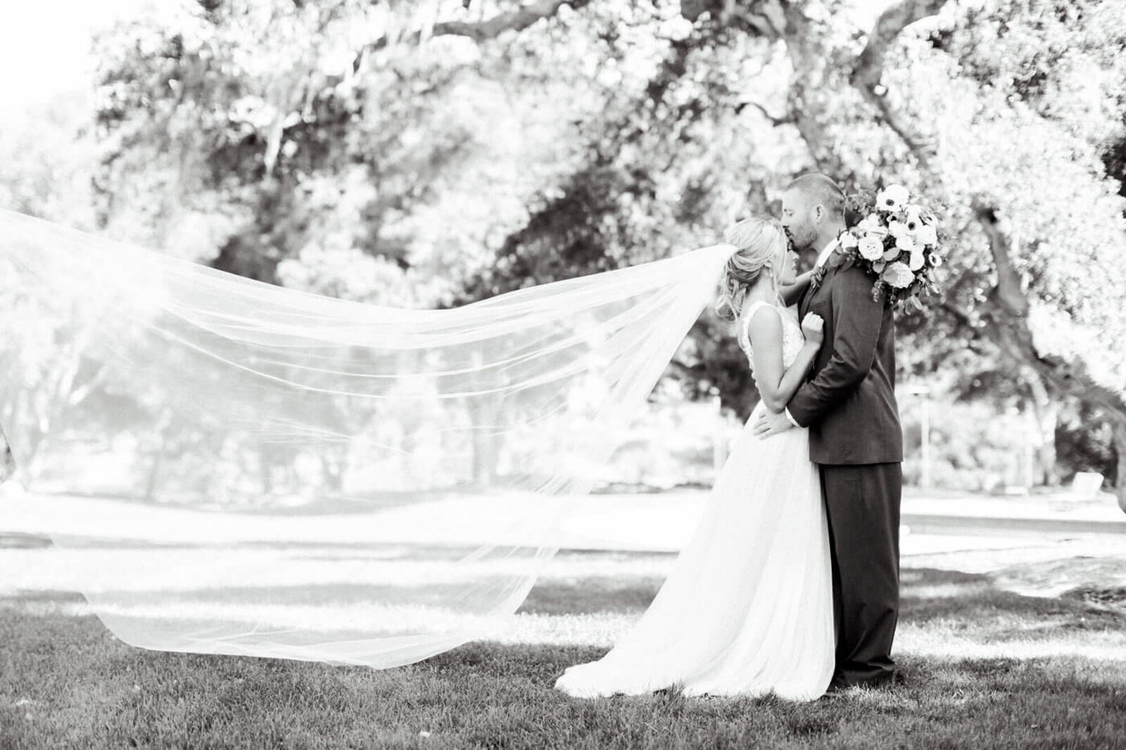 Black and white photo of couple, the groom kissing the forehead of the bride