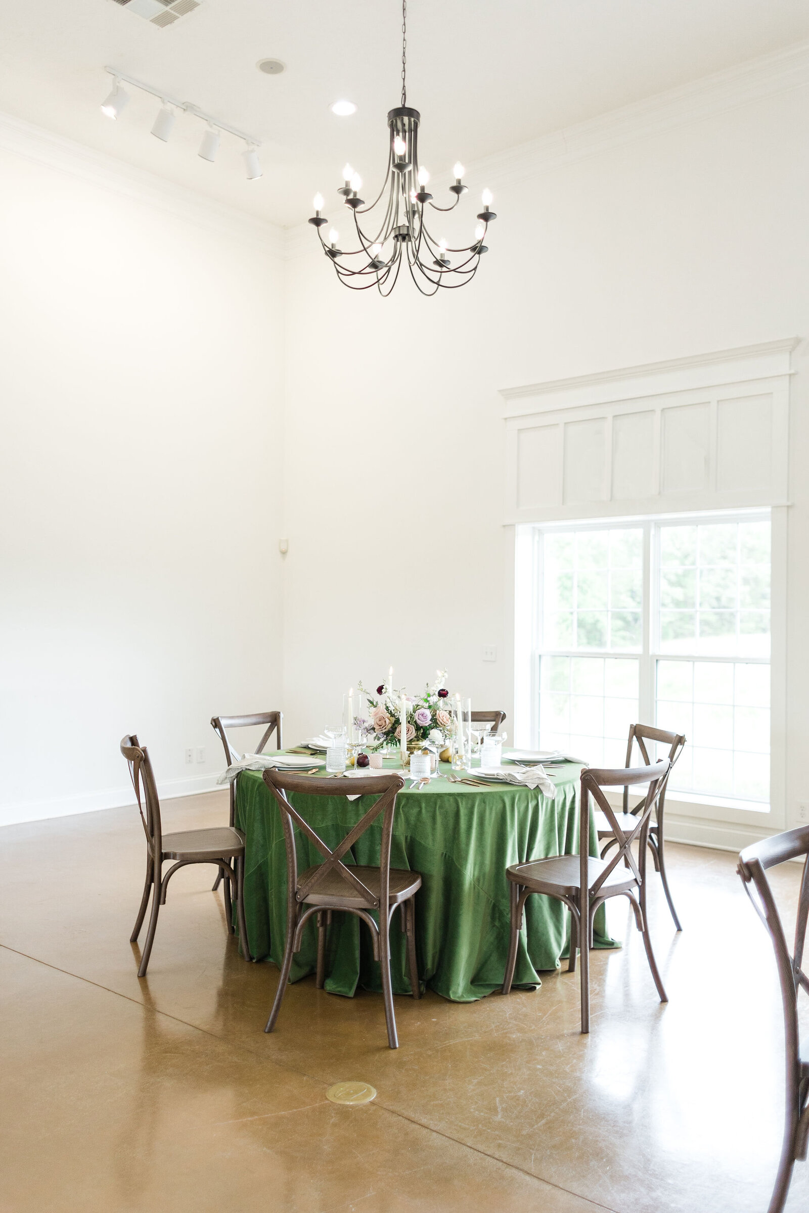 Wedding reception table featuring green linens, cross-back chairs, and floral centerpieces at Willow and Stone Events in Mocksville, NC.