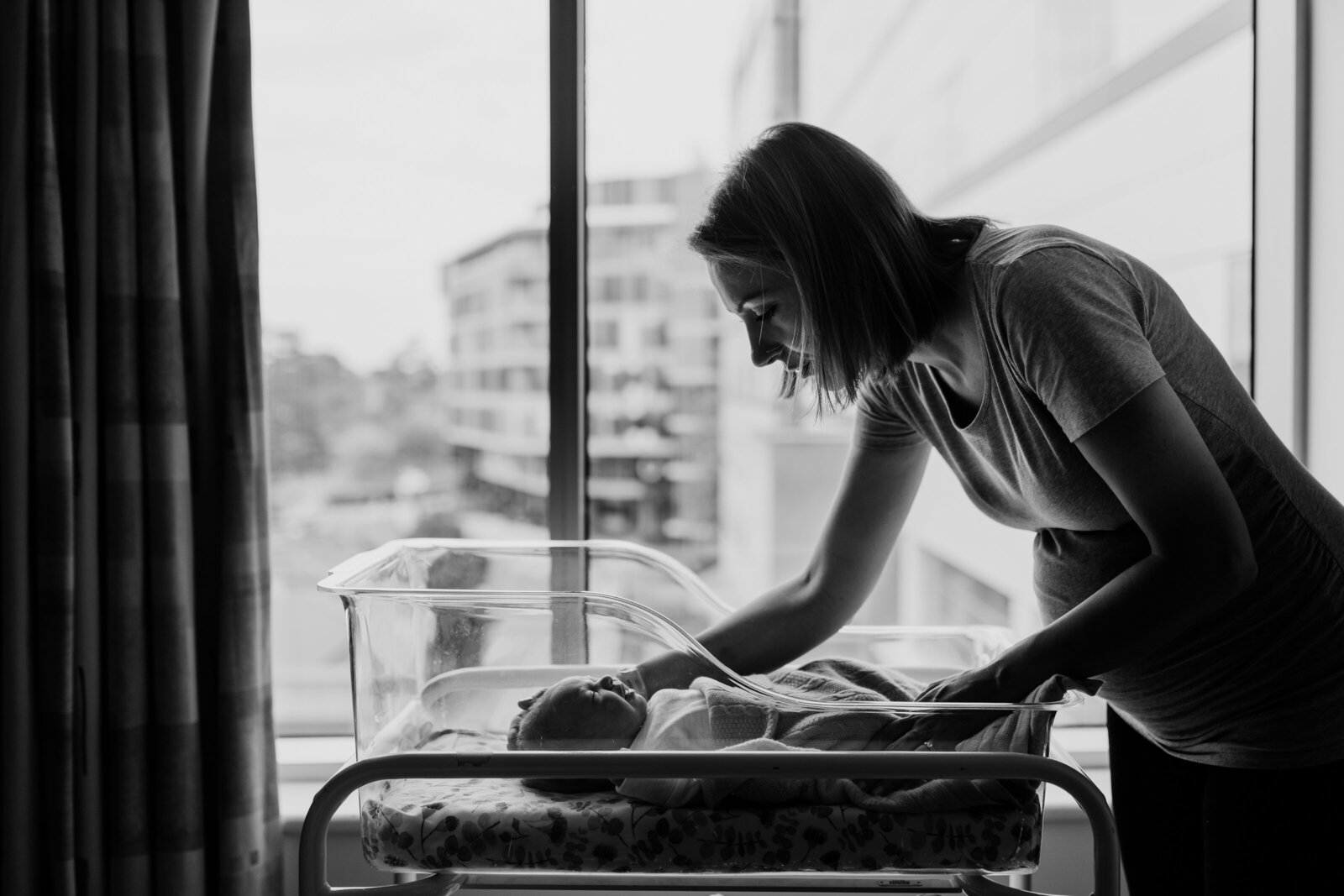 woman leaning over baby in bassinette in front of hospital window, Melbourne fresh 48 photography