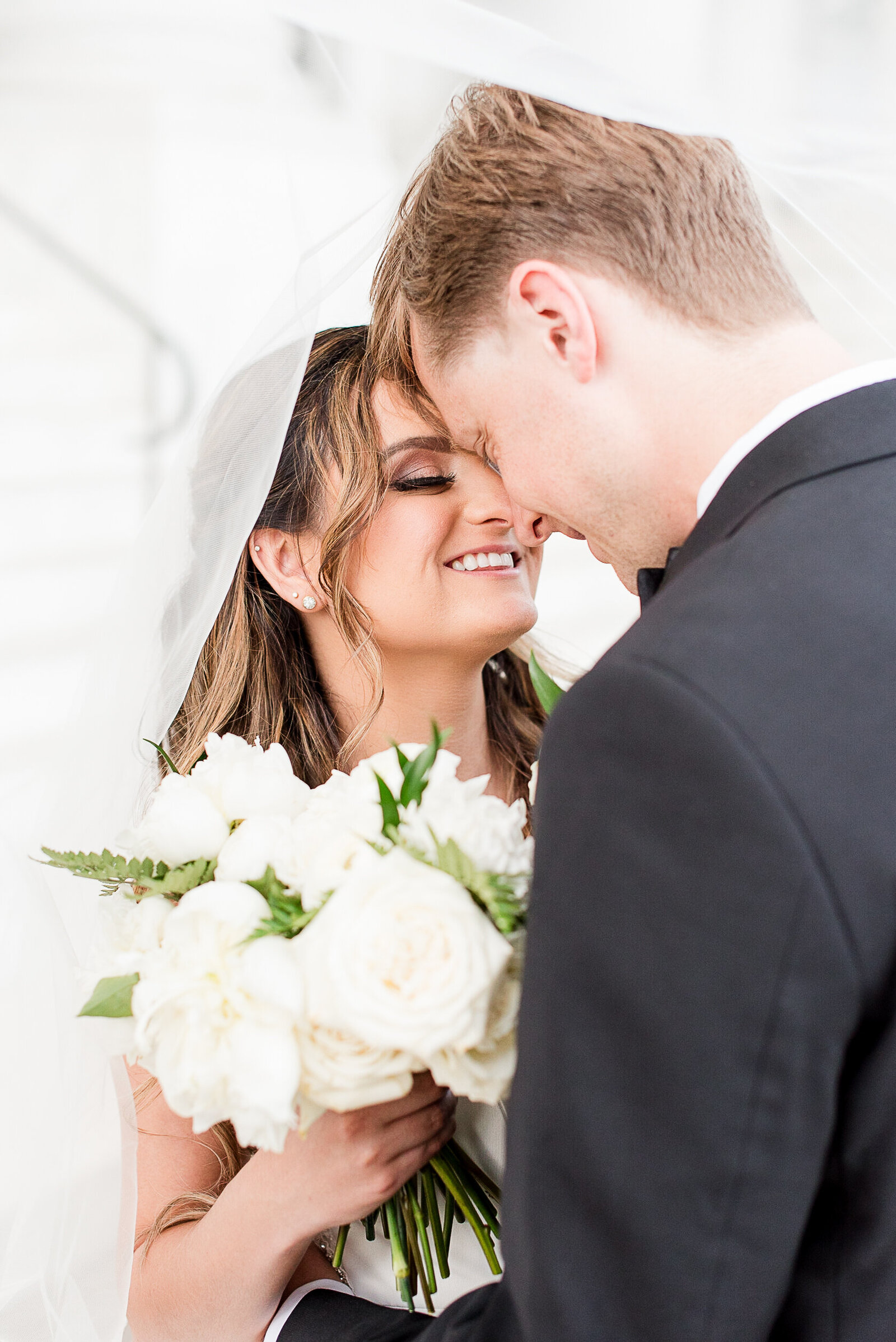 timeless bride and groom under veil with white florals