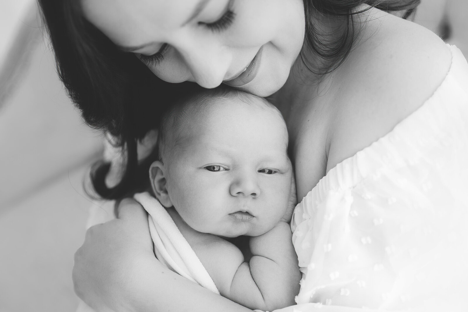 black and white Northern Virginia Newborn Photography of mom cuddling swaddled baby with eyes open looking at camera