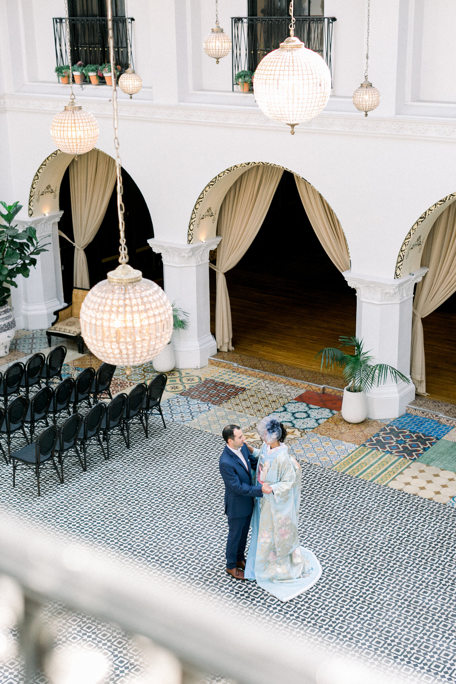 Overhead view of bride and groom dancing in the grand courtyard while she wears a blue floral wedding kimono at The Ebell Club Long Beach, available for kimono rental in Los Angeles | ロサンゼルスThe Ebell Club Long Beachの広い中庭で青い花柄の花嫁着物レンタル姿の新婦と新郎を見下ろすアングル