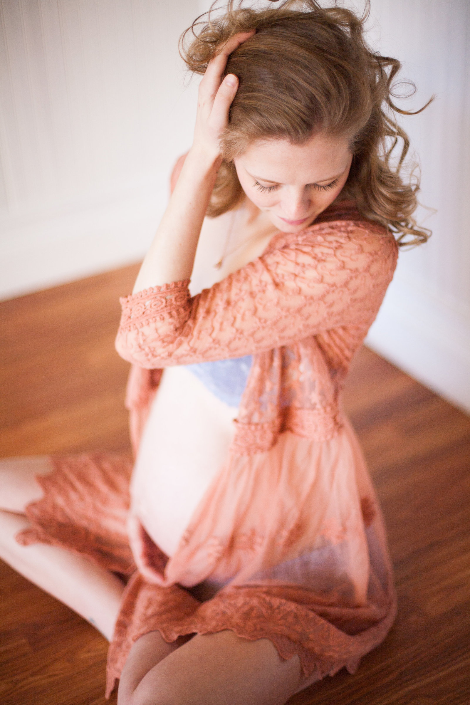 A maternity boudoir photo of a woman wearing a sheer shawl.