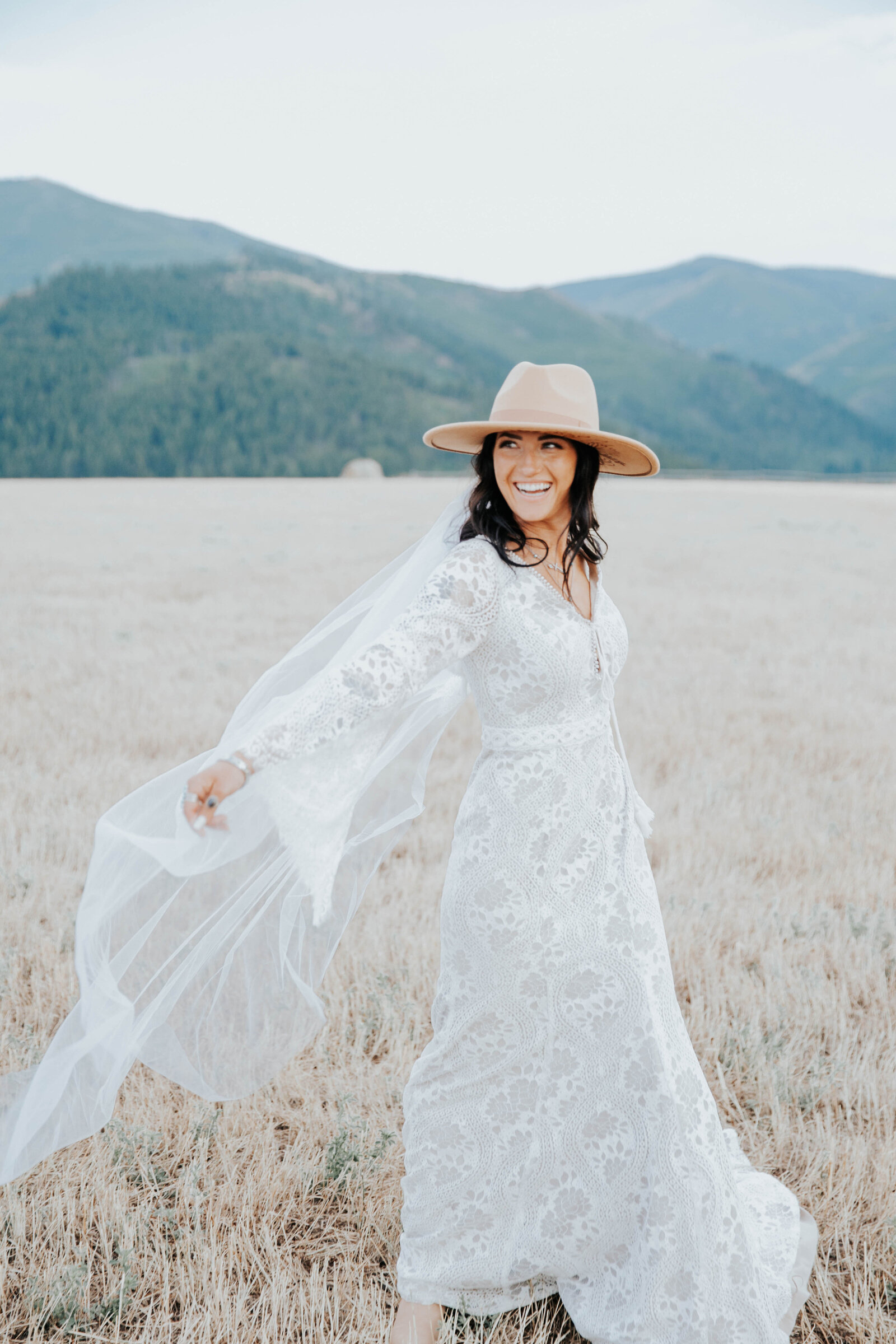 Bride swishes her wedding dress back and forth through the windy fields of Idaho captured by Idaho Falls Wedding Photographer