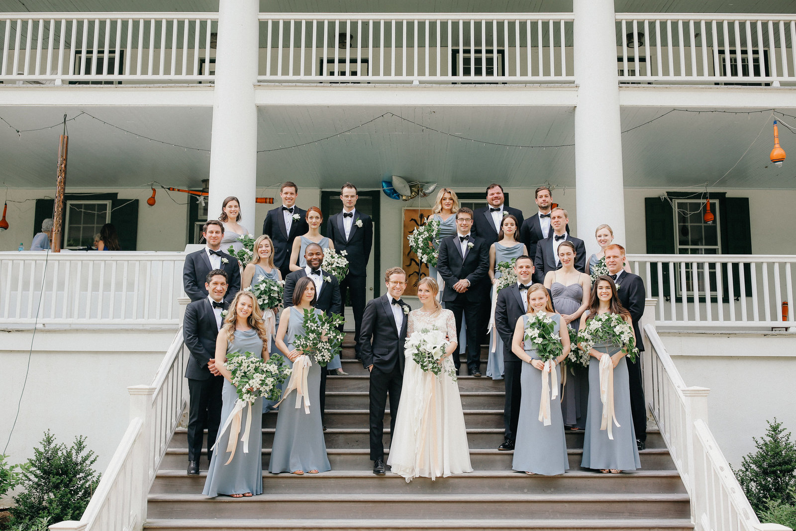 Whole bridal party pose together for a shot on the steps of the family's farm house estate.