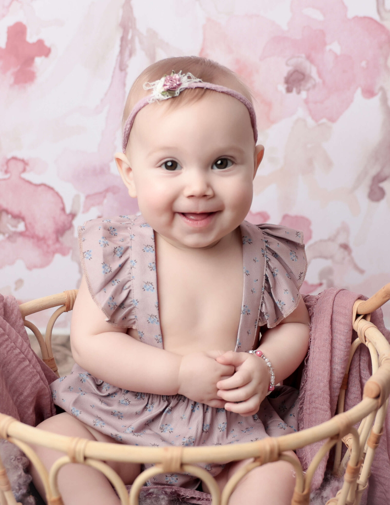 A joyful six-month-old baby smiling during a studio photography session in Rochester, NY, surrounded by colorful props.