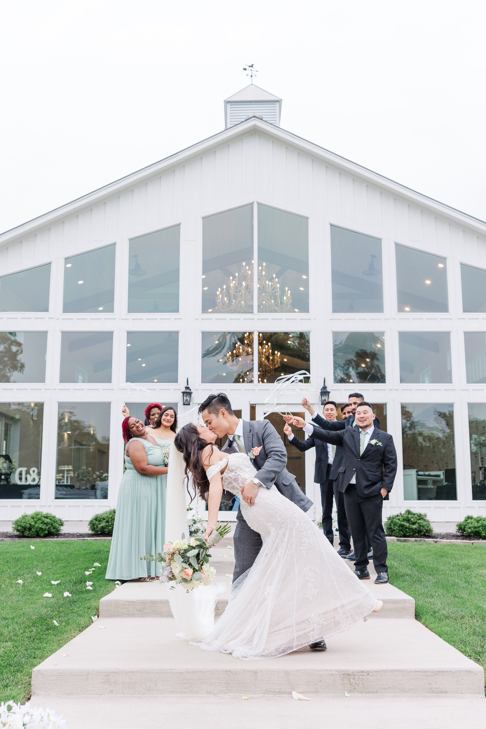 Bride and groom kiss after wedding ceremony with bridal party cheering